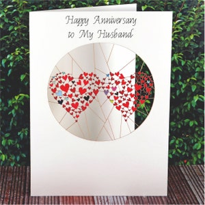 May include: A white card with the text "Happy Anniversary to My Husband" and a red and white heart design.
