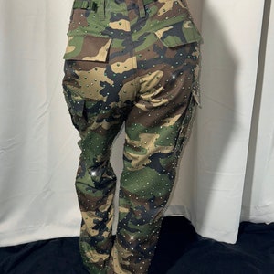 The back view of military camouflage pants. You can cleary see the pockets on the bottom part. The pants are bedazzled with rhinestones