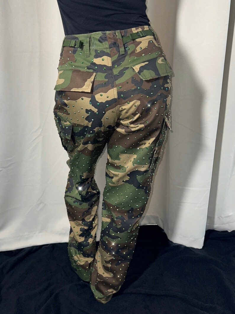 The back view of military camouflage pants. You can cleary see the pockets on the bottom part. The pants are bedazzled with rhinestones