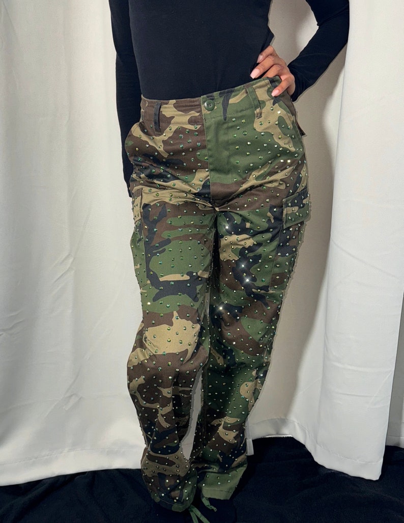 Front view of camouflage cargo trouser, a pocket on each side of the legs. There is a lace on the bottom of each side to pull the trousers tighter. The custom made trousers are adorned with rhinestones all over.