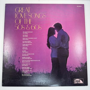 May include: Vintage vinyl record album cover titled "Great Love Songs of the 50's & 60's." The cover features a silhouette of a couple embracing against a pink and purple background. The album lists song titles and artist names.