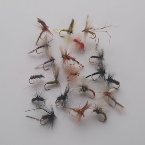 May include: A collection of 20 fly fishing lures with various colors and patterns, including black, white, brown, green, and red.
