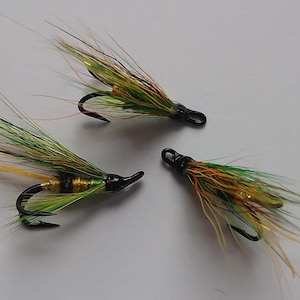 May include: Three green, yellow, and white fly fishing lures with black hooks.
