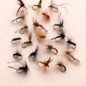 May include: A collection of various artificial fishing flies, each with a small hook and colorful, textured bodies. The flies feature a range of colors, including brown, black, red, and green, and are designed to mimic insects.
