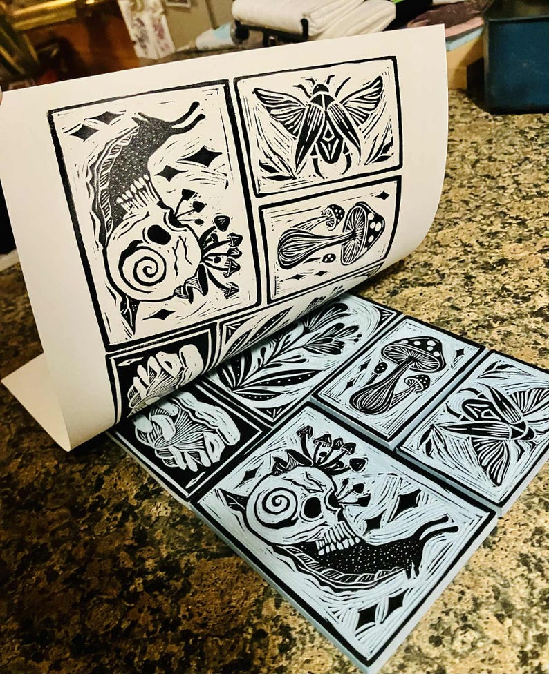 Peut inclure: Estampes en linogravure en noir et blanc repr&eacute;sentant un cr&acirc;ne, des champignons, un papillon de nuit et des feuilles. Les estampes sont dispos&eacute;es en grille, la feuille sup&eacute;rieure &eacute;tant soulev&eacute;e pour r&eacute;v&eacute;ler les estampes en dessous. Fond bleu clair.