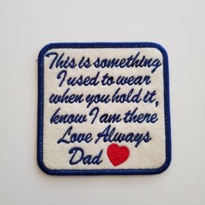 May include: Embroidered patch with a white background and a blue border. The patch features the text "This is something I used to wear when you hold it, know I am there Love Always Dad" in blue script, with a red heart.