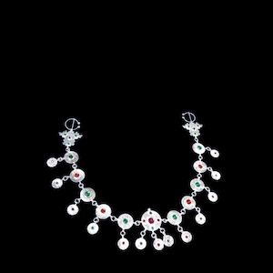 Peut inclure: Un collier en argent orné de pendentifs circulaires sertis de pierres précieuses rouges et vertes. Le collier présente un design délicat avec des accents pendants, sur fond noir. Le design est complexe.