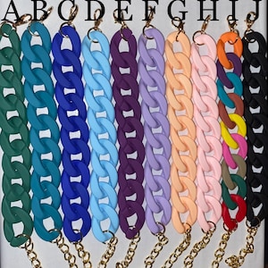 May include: A selection of colourful, chunky chain straps for handbags. The straps are in various colours, including green, blue, purple, and orange. Each chain is connected to a gold-coloured chain and clasp.