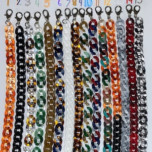 Peut inclure: Quinze chaînes en plastique de différentes couleurs. Les chaînes sont toutes de la même taille et du même style, mais chacune a un motif de couleur différent. Les chaînes sont suspendues à des crochets.