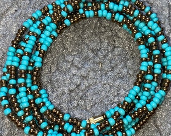 May include: A turquoise and brown beaded waist chain with a metal clasp. The chain is made of small, round beads and is wrapped around itself multiple times.