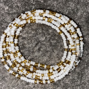 Peut inclure: Des perles de taille pour la taille, blanches et dorées, avec un fermoir argenté. Les perles sont disposées en alternance de perles blanches et dorées.