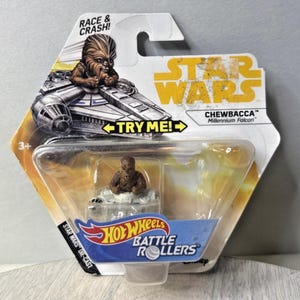 Puede incluir: Un juguete de fundición a presión Hot Wheels Battle Rollers con Chewbacca en el Halcón Milenario. El embalaje incluye el logotipo de Star Wars, el texto "Race & Crash!" y "Try Me!". El juguete está recomendado para mayores de 3 años.