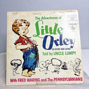 May include: Vintage vinyl record album cover for "The Adventures of Little Orley" featuring a cartoon illustration of a young boy in a red shirt and blue overalls. The title is in green and blue, with "Told by Uncle Lumpy" below.