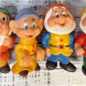 以下が含まれることがあります： 白い髭、カラフルなチュニック、帽子を身につけたキャラクターの成形プラスチック製フィギュア4体。青い眼鏡をかけたものを含む塗装された表情が特徴で、赤、黄、青、緑の服を着ています。