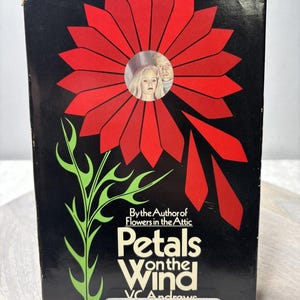 以下が含まれることがあります： V.C. Andrewsの「Petals on the Wind」というタイトルのヴィンテージ本。表紙は、黒い背景に大きな赤い花の模様があり、中央に2人の人物の円形画像があります。本は透明なスタンドに展示されています。