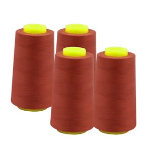 May include: Four spools of rust-colored thread with bright yellow tops and bases. The thread is tightly wound on conical spools, suitable for sewing and crafting projects. The spools are evenly spaced against a white background.