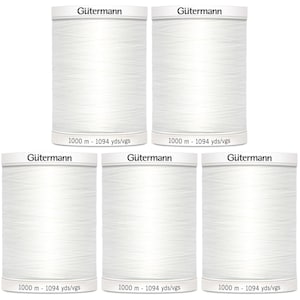 May include: Five spools of white Gütermann sewing thread arranged in two rows. Each cylindrical spool features the brand name Gütermann printed on the top and bottom, with the text 1000 m - 1094 yds/vgs clearly visible on the base of each unit.