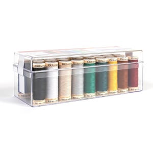 May include: A clear plastic box filled with spools of thread in various colors. The spools are labeled with the brand name "Gutermann" and the length of the thread, 100 m. The thread colors include black, white, beige, gray, green, yellow, brown, and burgundy.