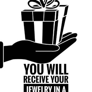 Puede incluir: Una ilustraci&oacute;n en blanco y negro de una mano sosteniendo una caja de regalo con un lazo en la parte superior. El texto debajo dice "Recibir&aacute;s tus joyas en una caja de regalo de lujo y una bolsa de regalo."