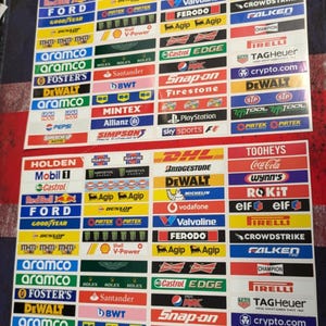 Könnte beinhalten: Zwei Bögen mit Aufklebern von Rennsponsoren mit Logos wie Holden, Ford, Mobil 1, Castrol und Red Bull. Die rechteckigen Aufkleber haben verschiedene Farben und Schriftarten.