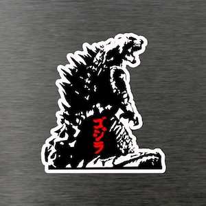 Könnte beinhalten: Schwarz-weiße Silhouette von Godzilla, einem riesigen Monster, mit dem japanischen Wort "ゴジラ" in roter Schrift an seiner Seite.