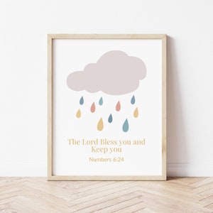 May include: A printable wall art design with a light purple cloud with raindrops in shades of blue, yellow, and pink. The text reads "The Lord Bless you and Keep you" with "Numbers 6:24" below.