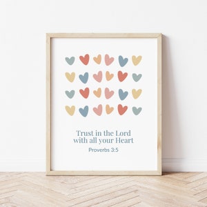May include: A framed print with a white background and a pattern of colorful hearts. The text "Trust in the Lord with all your Heart Proverbs 3:5" is printed below the hearts.