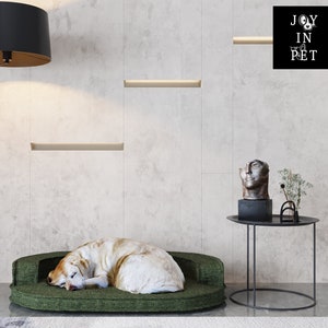 Op de afbeelding: Een groen hondenbed met een witte hond die erop slaapt. Het bed staat in een kamer met een zwarte staande lamp en een klein tafeltje met een beeld erop. De tekst "JOY IN PET" is zichtbaar in de rechterbovenhoek van de afbeelding.