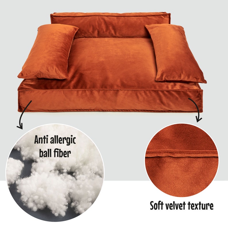 Peut inclure: Un grand lit pour chien rectangulaire de couleur orange br&ucirc;l&eacute; en velours avec deux oreillers. Le lit est rempli de fibres de balle anti-allergiques. Le texte "Anti allergic ball fiber" est &eacute;crit sur un cercle blanc dans le coin inf&eacute;rieur gauche de l'image. Le texte "Soft velvet texture" est &eacute;crit sur un cercle blanc dans le coin inf&eacute;rieur droit de l'image.