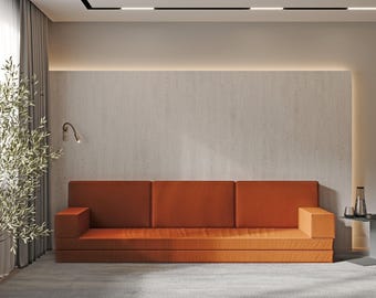 Könnte beinhalten: Ein dreiteiliges orangefarbenes Ecksofa mit einer hellbraunen Wand dahinter. Das Sofa hat ein modernes Design mit einem niedrigen Profil und einer schlichten, klaren Optik.