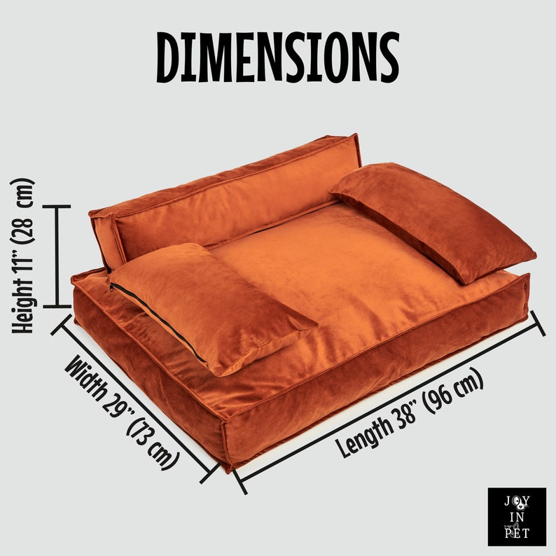Peut inclure: Un lit pour chien rectangulaire en velours orange avec un appui-t&ecirc;te sur&eacute;lev&eacute; et deux oreillers. Le lit mesure 96 cm de long, 73 cm de large et 28 cm de haut.