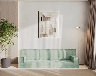 May include: A modern living room featuring a light green sofa with a geometric pattern, a framed abstract artwork, and a tall potted plant. A floor lamp and neutral-toned rug complete the space.