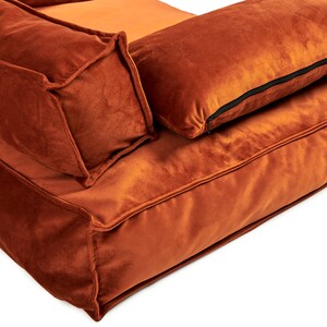 Peut inclure: Un canap&eacute; en velours orange br&ucirc;l&eacute; avec deux coussins assortis. Le canap&eacute; a un design capitonn&eacute; et une assise profonde et confortable.