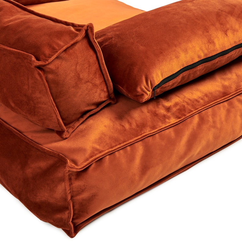 Peut inclure: Un canap&eacute; en velours orange br&ucirc;l&eacute; avec deux coussins assortis. Le canap&eacute; a un design capitonn&eacute; et une assise profonde et confortable.