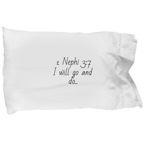 May include: White pillow with black text that reads "1 Nephi 3:7 I will go and do..."