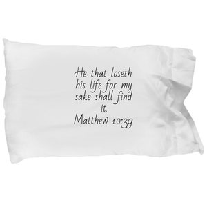 May include: White pillow with black text that reads "He that loseth his life for my sake shall find it. Matthew 10:39"
