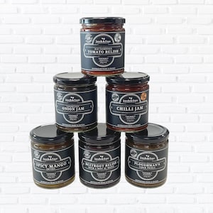 May include: Six glass jars of gourmet condiments with black labels and white text. The jars are arranged in a pyramid shape. The labels read: Old Fashioned Tomato Relish, Onion Jam, Chilli Jam, Spicy Mango Chutney, Beetroot Relish with a Hint of Maple, and Ploughman's Cider Pickle.