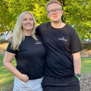 May include: A woman and a man wearing black t-shirts with the text "Josh & Sue" printed on them. The woman is wearing a white skirt and the man is wearing black shorts.