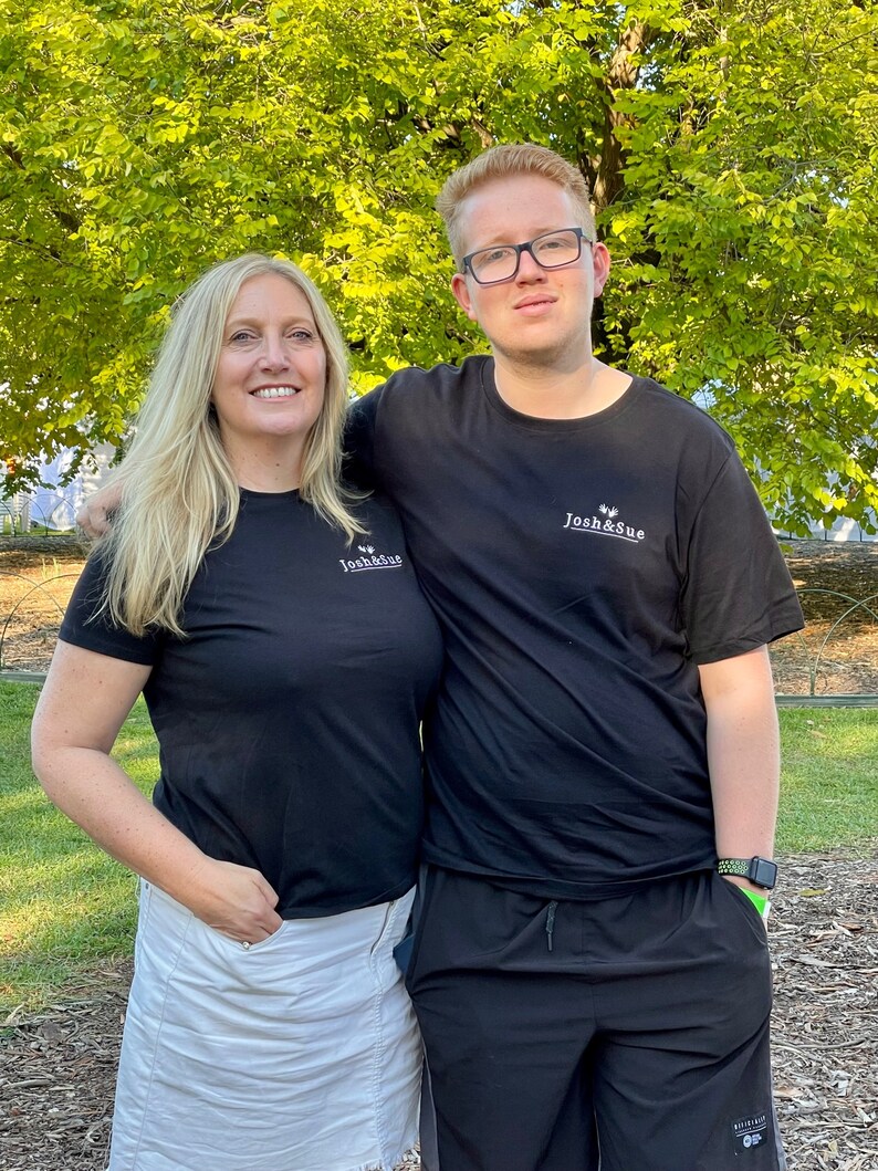 May include: A woman and a man wearing black t-shirts with the text "Josh & Sue" printed on them. The woman is wearing a white skirt and the man is wearing black shorts.