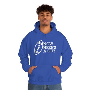 May include: A royal blue hooded sweatshirt with a white football graphic and the text "NOW HERE'S A GUY".