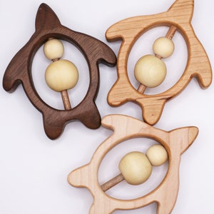 May include: Three wooden turtle rattles, one brown and two natural wood. Each rattle has a wooden dowel with two wooden beads.