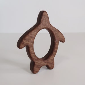 May include: A wooden turtle shaped teether for babies. The teether is made of dark brown wood and has a smooth, rounded surface.