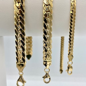 May include: Three gold chain bracelets with a curb link design. The bracelets are displayed on a white background.