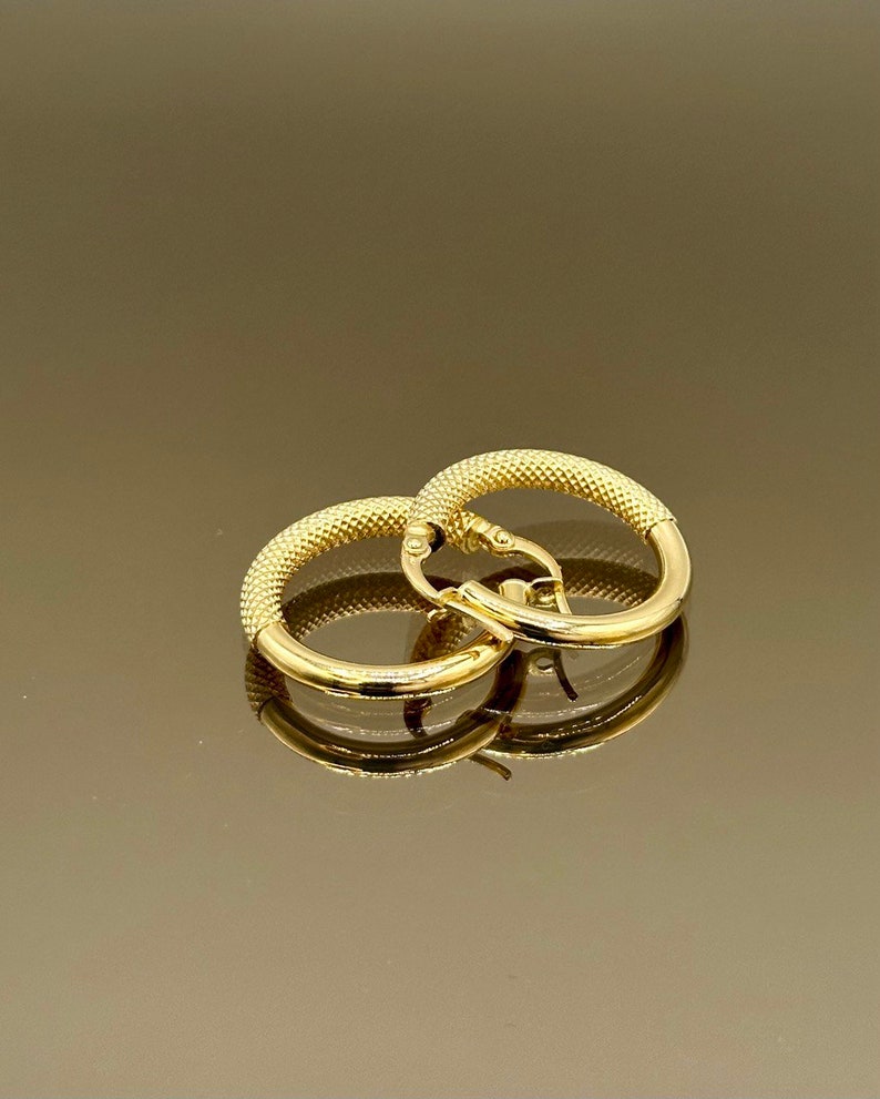 May include: A pair of gold hoop earrings with a textured surface.