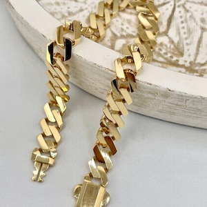 May include: A gold chain bracelet with a curb link design. The bracelet has a clasp closure.