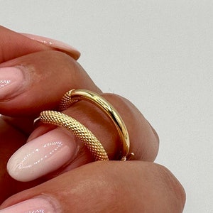 May include: Two gold hoop earrings, one with a smooth finish and the other with a textured finish. The earrings are shown on a hand with pink nail polish.
