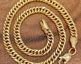 May include: A gold chain necklace with a curb link design. The chain is thick and has a shiny finish.