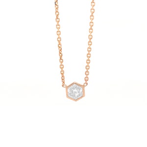 May include: A rose gold chain necklace featuring a single hexagonal pendant. The pendant is set with a clear, faceted, hexagonal-shaped stone that reflects light, held securely within a thin rose gold metal frame attached to the delicate chain.