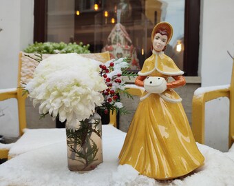 A gentle, charming and graceful lady figurine with a muff in a bright yellow winter outfit, 1960s-1980s.