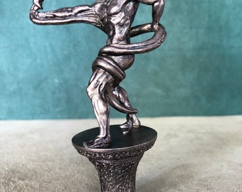 May include: A bronze statue of a muscular figure with a snake wrapped around its body. The figure is standing on a decorative base.
